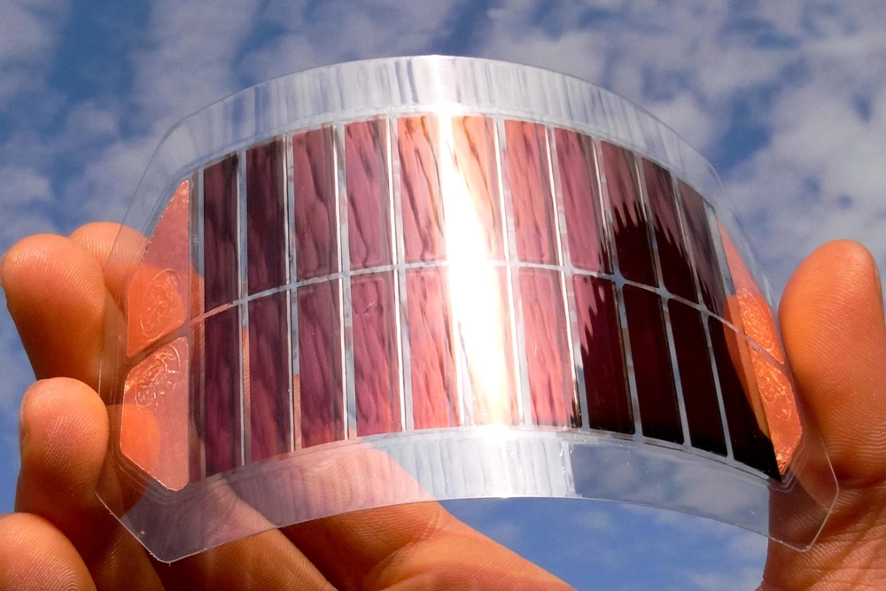 Flexible solar cell sligthly bent in hand with sky background