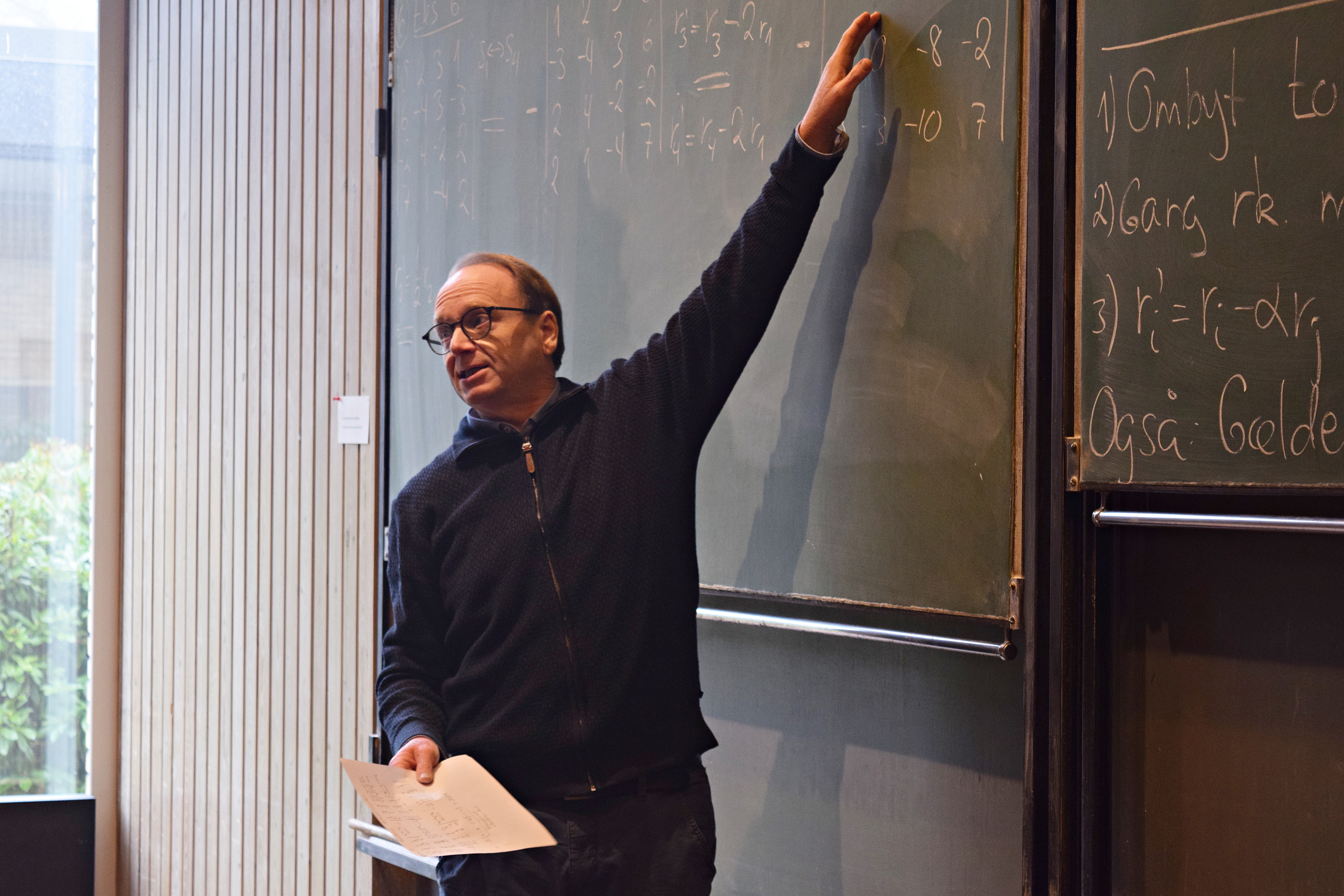 Lars Staalhagen teaching, pointing at a blackboard with formulas written on it