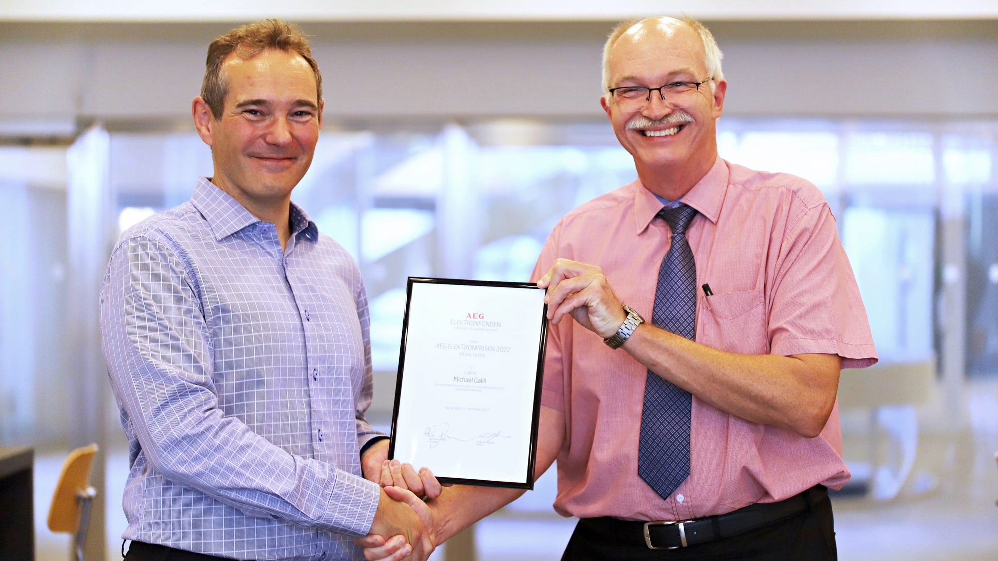 Associate professor Michael Galili is awarded AEG Elektronprisen 2023, photographed holding the certificate shaking hands with the President og DTU Anders Bjarklev