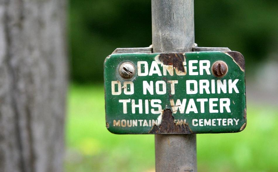 Worn down sign that reads "Danger, do not drink this water"